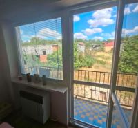 A room with a balcony, wooden decor flooring, and a garden view in a 3-room apartment.