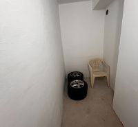 A small room with white walls in a 2-room apartment with tires and a plastic chair.