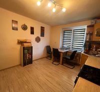 A kitchen in a 2-room apartment with a wooden decor floor and furniture.