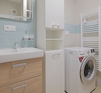 Bathroom with a washing machine and a sink in the interior of a studio apartment with blue tiles.