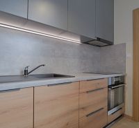 A kitchen in a studio apartment with a wood-patterned floor and built-in appliances.