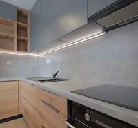 A kitchen with wooden cabinets and built-in appliances in a studio apartment.
