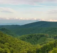 Mountain forests and hills surrounding agricultural and forest lands near Veľké Ozorovce.