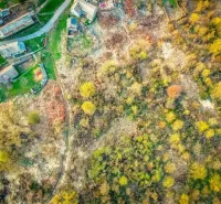 Aerial view of plots - housing in the village of Muľa, surrounded by greenery and a road.