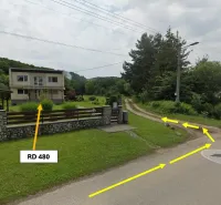 A family house and gardens in Bystré by the road with signposts.