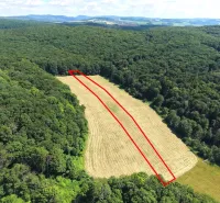 Aerial view of a field surrounded by forests in Záhrady near Podbranč.