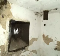 Plastered interior of a peculiar property with a metal hatch in the wall.