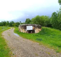 Bunker from special properties in Malacky, surrounding trees and a watered gravel road.