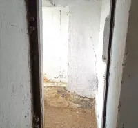A narrow concrete hallway in Special Properties with light walls and a brown floor.