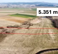 Agricultural and forest lands in Podhorany with marked plot area on flat fields.