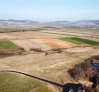 Agricultural and forest lands in Podhorany with a river between the fields and the mountain range.