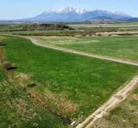 Agricultural and forest lands in Podhorany, with a road and distant mountains on the horizon.