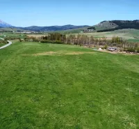 Panorama of agricultural and forest lands in Podhorany with a mountain background and a road.