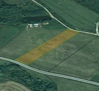 Agricultural and forest lands in Podhorany with arable field and access road.