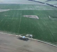 Aerial view of green agricultural and forest lands in Podhorany with scattered areas.