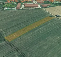 Agricultural and forest land in Podhorany with a marked field near the urbanized area.