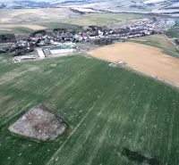 Aerial view of agricultural and forest lands around Podhorany with the village in the background.