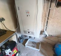 Boiler in the basement area of the family house, next to the compressor and the shelf.