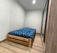 Bedroom in a family house with a bed, wardrobe, and wooden decor flooring.