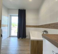 A bathroom with a bathtub and a wooden decor floor in a family house.