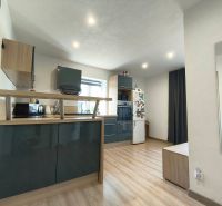 A kitchen in a family house with a wooden decor floor, light walls, and modern equipment.