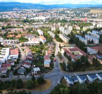 Aerial view of a residential area and gardens in Zvolen, with a hilly background.