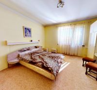 A bedroom in a family house with a bed and a built-in wardrobe, light yellow walls.