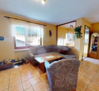 Living room with a comfortable sofa and a fireplace in a family house, floor with ceramic tiles.