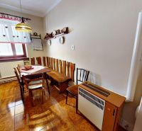 A kitchen in a family house with a wooden table and chairs, decorations on the walls, and a floor with a wooden design.