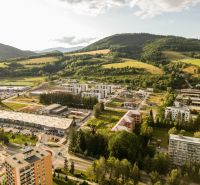 Aerial view of Plots - housing in the Barracks District, Brezno, with surrounding green hills.