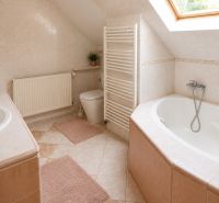 A bathroom in a family house with a bathtub, a skylight, and tiles.