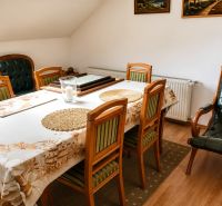Dining room in a family house with wooden furniture and a wood-patterned floor.
