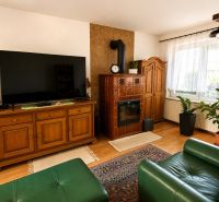 Living room in a family house with a tiled stove, television, and wooden decor.
