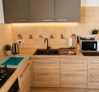 A kitchen with tiles and a wooden decor floor in a family house.