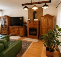 Living room with wood-patterned flooring, green sofa, and wooden furniture in a family house.
