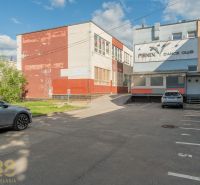 A building in Banská Bystrica with parked cars in front of the dance club in the parking lot.