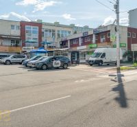 A street with a building in Banská Bystrica, cars, and advertising signs on businesses.