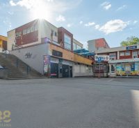 A building in Banská Bystrica with shops and a staircase, sunny day.