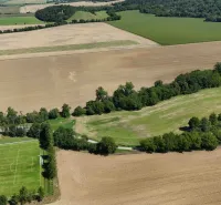 Panorama of agricultural and forest landscape near Nová Ves nad Váhom with a football field.