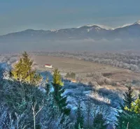 Winter landscape around Nolčovo with snow-covered agricultural and forest lands and mountains in the background.