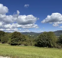 Landscape in Hankovce with agricultural and forest lands, blue sky, clouds.