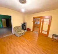 Interior of a family house with a wooden decor floor, a comfortable armchair, and a fireplace.