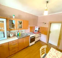 A kitchen in a family house with a wooden decor floor and wooden cabinets.