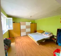 A room in a family house with a wooden decor floor, green walls, and furniture.