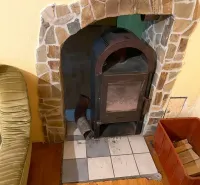A wood-burning stove in a family house with a wooden decor floor next to a comfortable armchair.