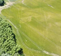 Aerial view of agricultural and forest land in Kozárovce, green landscape with a field.