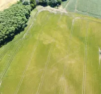 An aerial view of agricultural and forest land near Kozárovce, surrounded by fields and forests.