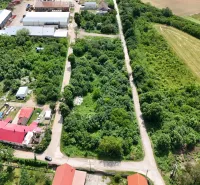 An aerial view of vegetation-covered residential plots in Parchovany, bordered by roads and buildings.