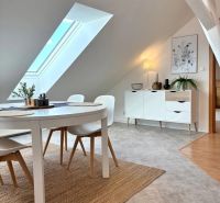 Dining area with a table in an attic 4-room apartment with a large skylight.