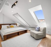 Attic bedroom with a large bed, armchair, and floor with wooden decor.